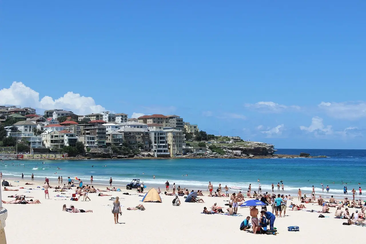 Golden sand beach with surfers and swimmers, iconic Bondi pavilion in background
