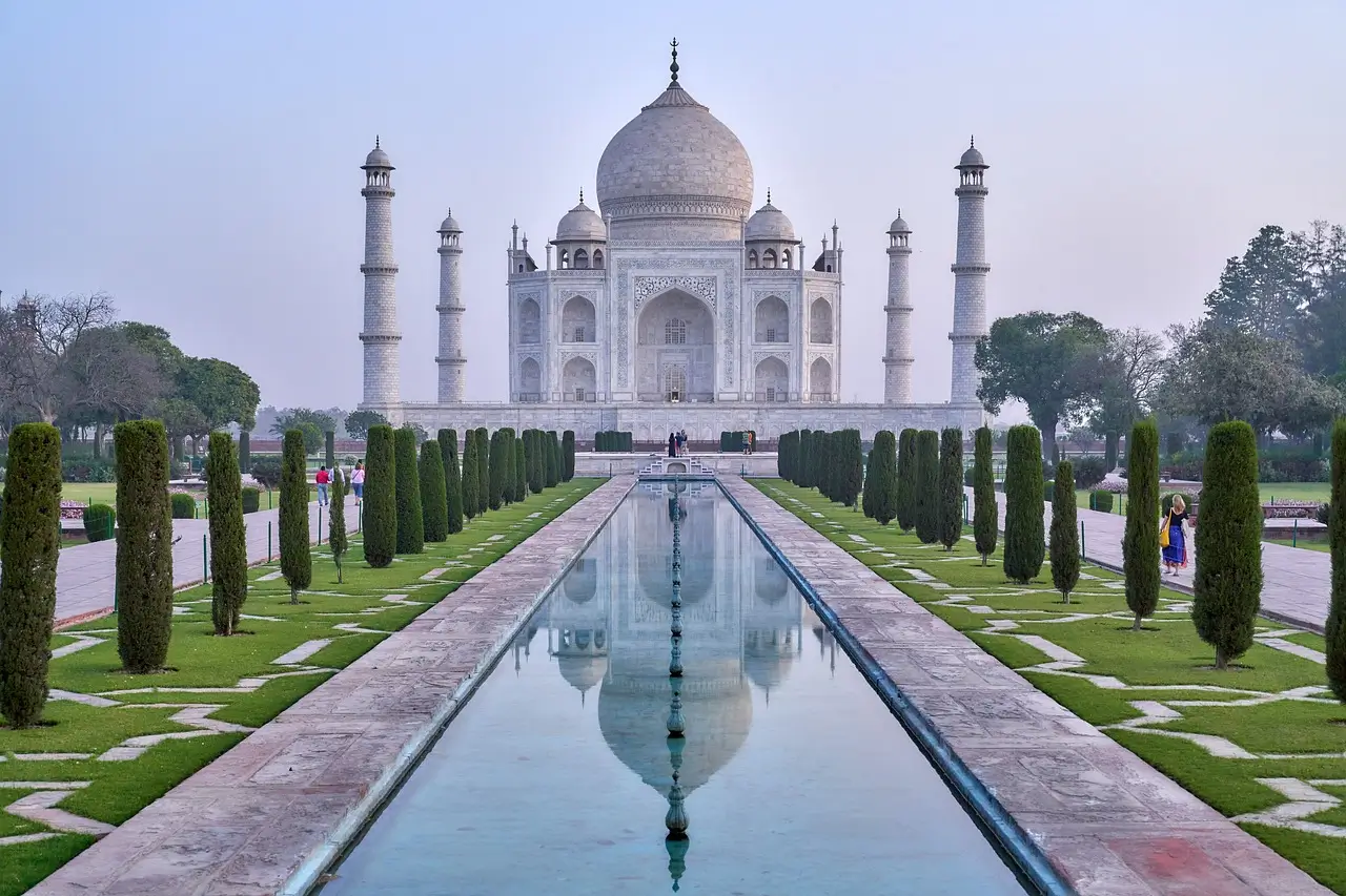 Taj Mahal white marble dome and minarets reflected in water at sunrise