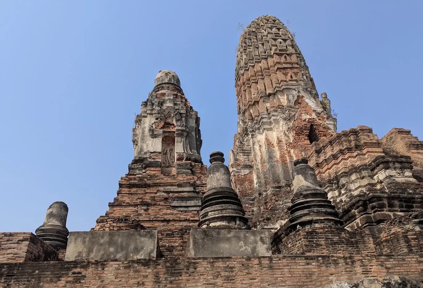 Ancient Buddhist temple ruins with headless Buddha statues and brick structures against blue sky