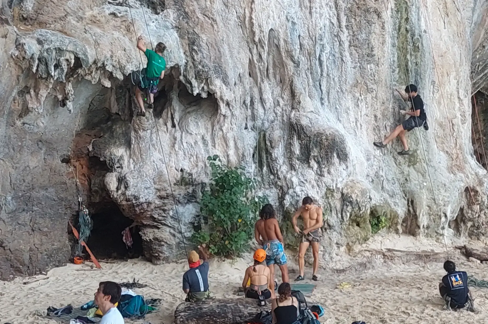 Dramatic limestone cliffs rising from clear turquoise water with longtail boats on white sand beach